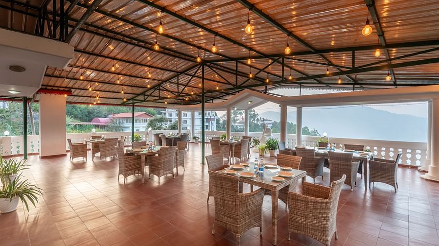 Covered terrace at DLS Tehri Club Resort with tables and chairs, perfect for enjoying the views.